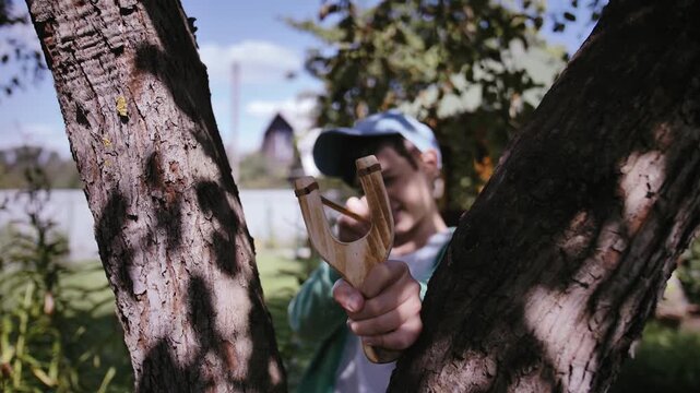 Sunny Summer Fun: Boy Enjoying Outdoor Play with a Slingshot