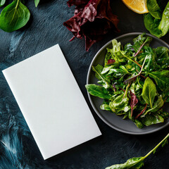 A white napkin sits on a plate of salad. The salad is full of greens and has a few pieces of lemon