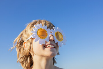 cheerful portrait of a happy child on a sunny day against blue sky. A sincere smile, daisy-shaped...
