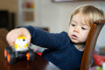Adorable toddler boy sitting in the living room and playing with a toy