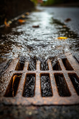 Storm drain hatch collects rainwater on a rainy day in a city street