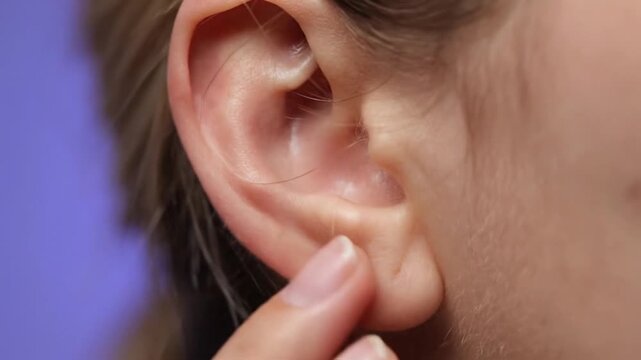 Closeup of a persons ear highlighting the intricate details of the outer ear structure and skin texture.