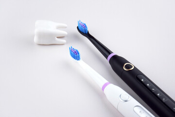 Modern electric ultrasonic toothbrush with rechargeable battery on a gray surface.