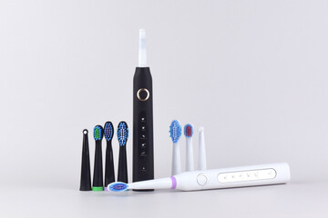 Modern electric ultrasonic toothbrush with rechargeable battery on a gray surface.