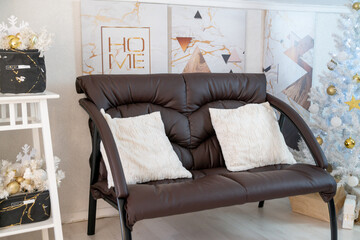 Christmas interior of a bright living room. The attic. A white Christmas tree with a brown sofa. Daytime.