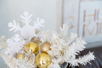 Christmas composition with white spruce branches and golden balls in the interior of a bright living room