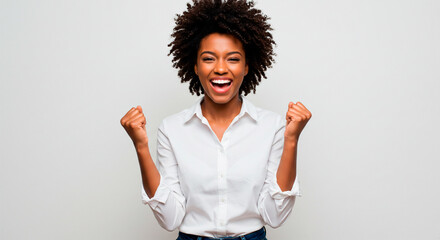 Radiant black woman celebrating success, raising fists in triumph on white background