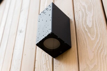 black front lamp on the wooden facade of a house with rain or dew drops