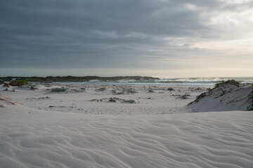 A coastline under dark clouds with silver sand dunes, South Africa