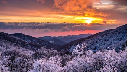Obraz premium Winter wonderland hills covered in frost with vivid sunset, clouds, and layers of mountain ranges