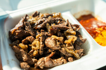 Close-up of a traditional Namibian grilled meat dish served in a takeaway container in Usakos, Namibia