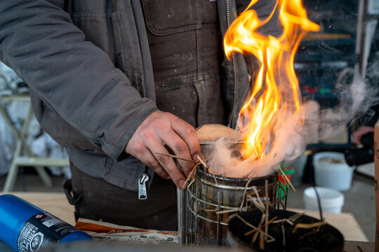 A beekeeper ignites a smoker to calm bees before inspecting hives at Dancing Bee Farm in Port Hope, Ontario, Canada, symbolizing safety, skill, and care in sustainable beekeeping