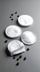 Three white circular cotton rounds, coffee beans scattered around