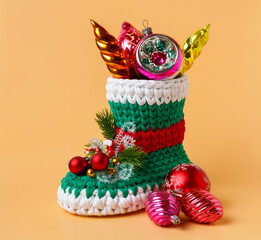 A beautiful, knitted Christmas shoe filled with shiny antique toys, on an orange background