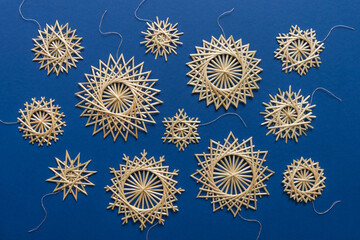 Snowflakes are made of straw on a blue background. Christmas decor. Top view. Straw weaving. Lutsk, Ukraine
