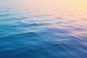 Naklejka premium Tranquil Morning Surf A calm, glassy ocean surface reflecting a soft, misty morning sky. Gentle ripples indicate incoming waves. Pastel colors and a serene atmosphere. No people or human elements