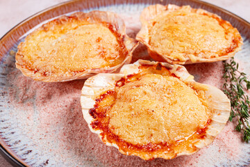 scallop, baked in shells, with cheese and spices, on a plate, homemade,