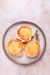 scallop, baked in shells, with cheese and spices, on a plate, homemade,