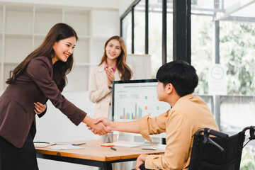 Young professional woman warmly shaking hands with seated colleague wheelchair office during successful presentation, inclusive and positive