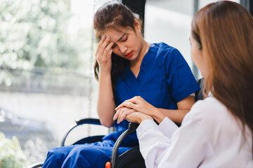 Distressed patient sitting in wheelchair comforted by doctor holding her hand, compassionate support in medical setting