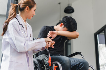 Young male patient in wheelchair covering face while female doctor comforts him with empathy and supportive touch