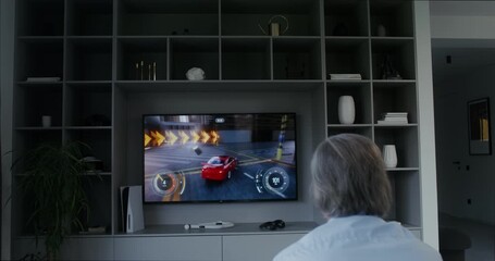 Old man playing racing video game at home - Powered by Adobe