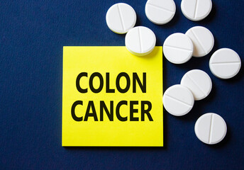 Colon Cancer symbol. Concept word Colon Cancer on yellow note. Beautiful deep blue background with pills. Medicine and Colon Cancer concept. Copy space
