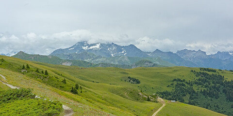 Obraz premium mountain landscape with green meadow and granite peaks with glaciers under a cloudy sky in La Vanoise nature reserve, Savoie, France 