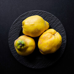 Stillleben - Drei Prachtexemplare von gelben Quitten auf  schwarzen Untergrund