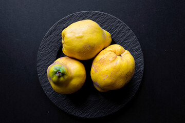 Drei Prachtexemplare von gelben Quitten auf  schwarzen Untergrund