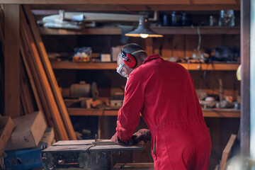 A craftsman cutting a board in his workshop.