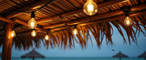 Fairy lights hanging under palm roof at beach during sunset  