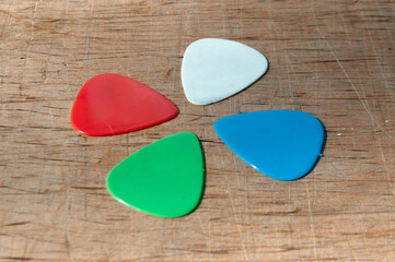 Four guitar picks forming a clover shape: red, white, blue, green