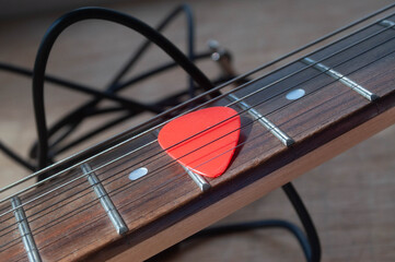 Red guitar pick, electric guitar neck and jack cable