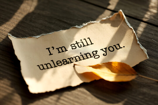 Torn paper with 'i'm still unlearning you' message symbolizing heartbreak and moving on