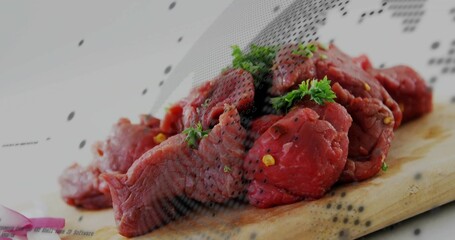 Lying raw beef chunks on wooden cutting board in kitchen with parsley, cracked pepper, onion slices