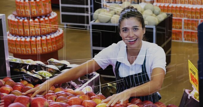 Organizing clerk in green-striped apron leaning over red apples at market produce, with juice trays - Powered by Adobe