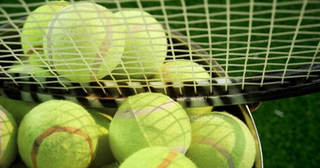 Displaying yellow tennis balls piling in wire basket on green court, tennis racket casting shadows © vectorfusionart