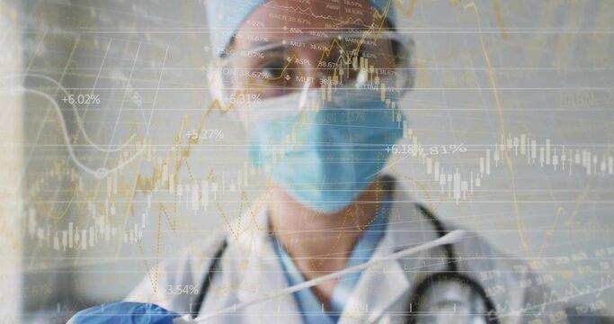 Female medical professional analyzing financial charts in corridor, wearing mask and stethoscope