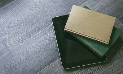 Traditional vs digital reading. Two paper books beside a modern tablet on a wood surface, Evolution of literature, information access concept. Ideal for articles on reading, technology, or education.