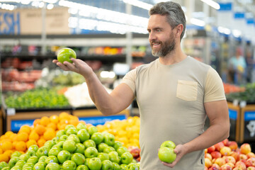 Man shops for fresh apples at a market. Customer chooses organic apples in a grocery store. A male...
