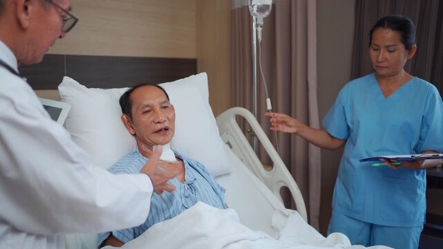 Doctor and nurse checking elderly tracheostomy patient in hospital.