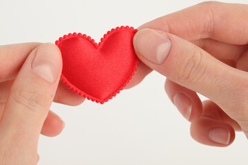Hands hold scalloped satin heart on white, symbolizing softness, care, and the quiet clarity of emotional offering