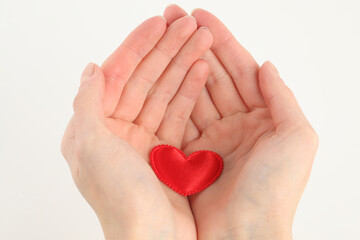 Fototapeta premium Hands cradle satin heart on white, symbolizing care, softness, and the quiet clarity of emotional offering