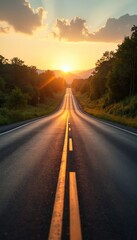 Long asphalt road extends into golden sunset. Sun flares brightly on horizon, bathing path, green trees in warm light. Rural scenery with clouds above. Scenic drive through country landscape at dusk,