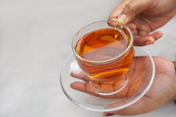 A glass cup of red tea isolated on a woman's hand isolated on white background. Healthy herbal drink. Top view and Selective focus.