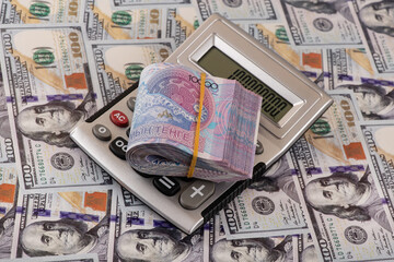 A stack of 10,000 Kazakhstani tenge bills and a calculator for 100 US dollar bills