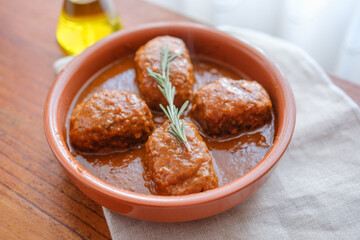 Tuna fish rolls in tomato sauce served in traditional clay dish with rosemary, Mediterranean homemade food, horizontal image with natural light.