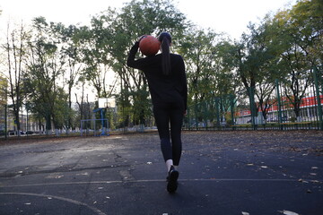 Fototapeta premium a young female athlete playing basketball from behind
