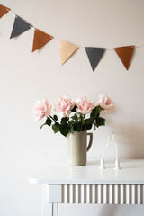 A vase of pink roses and candles on a white table, ideal for any special celebration.